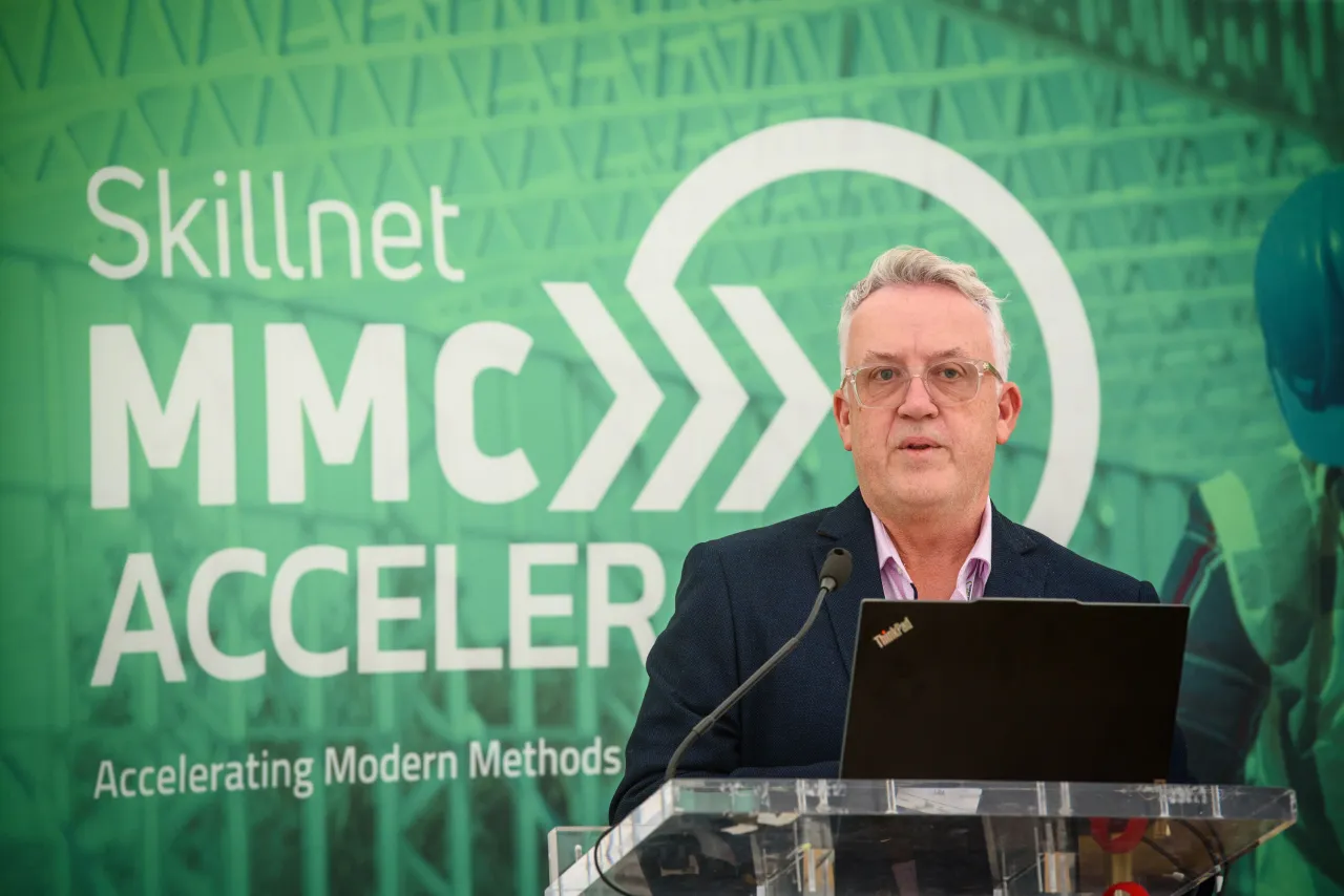 Person speaking at podium in front of green Skillnet MMC ACCELERATE banner