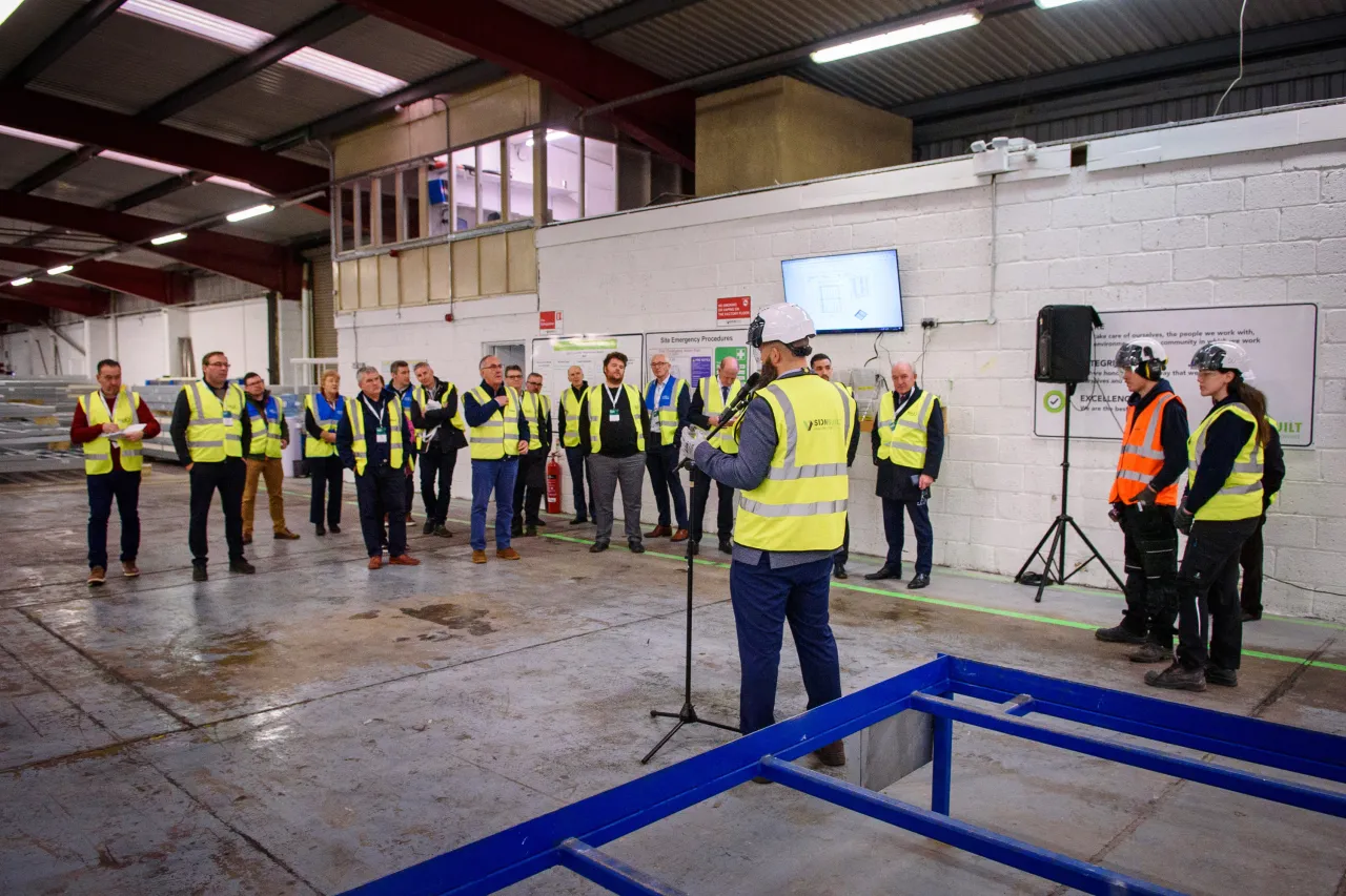 Workers in high-visibility vests gathered in an industrial warehouse space for safety training.