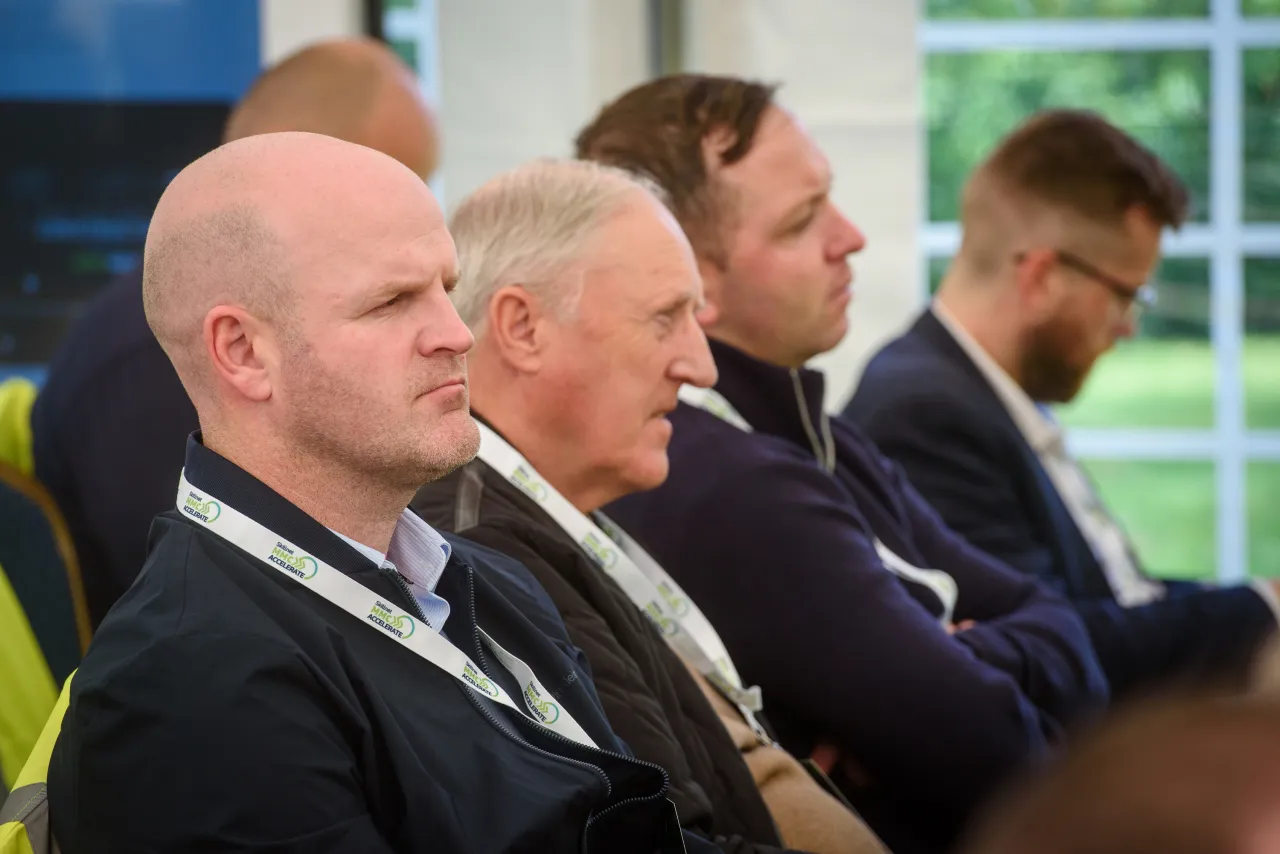 A row of formally dressed men sitting in a line at what appears to be a business meeting.