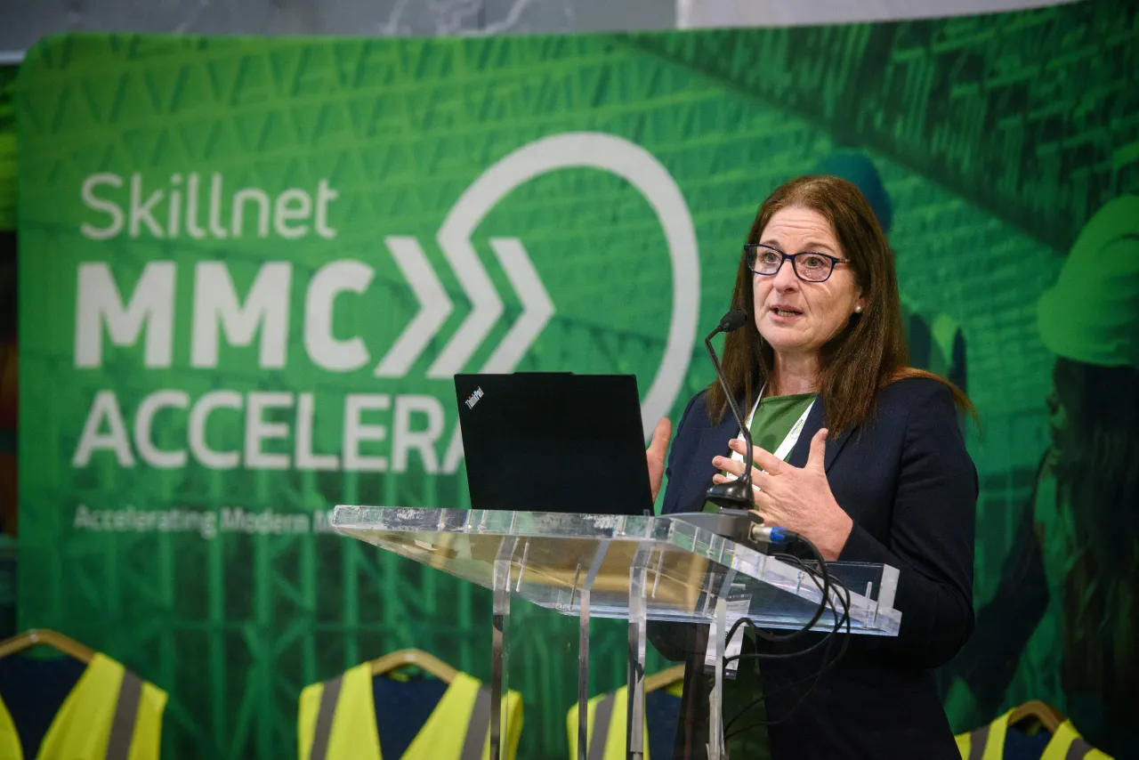 Woman speaking at a podium with Skillnet MMC Accelerate logo in the background.