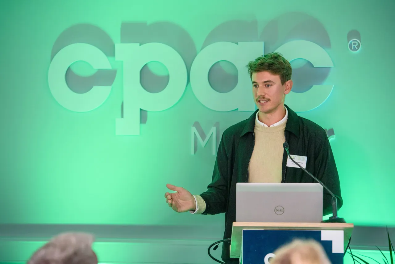 Person speaking at a podium with OPPO logo displayed on a green background.