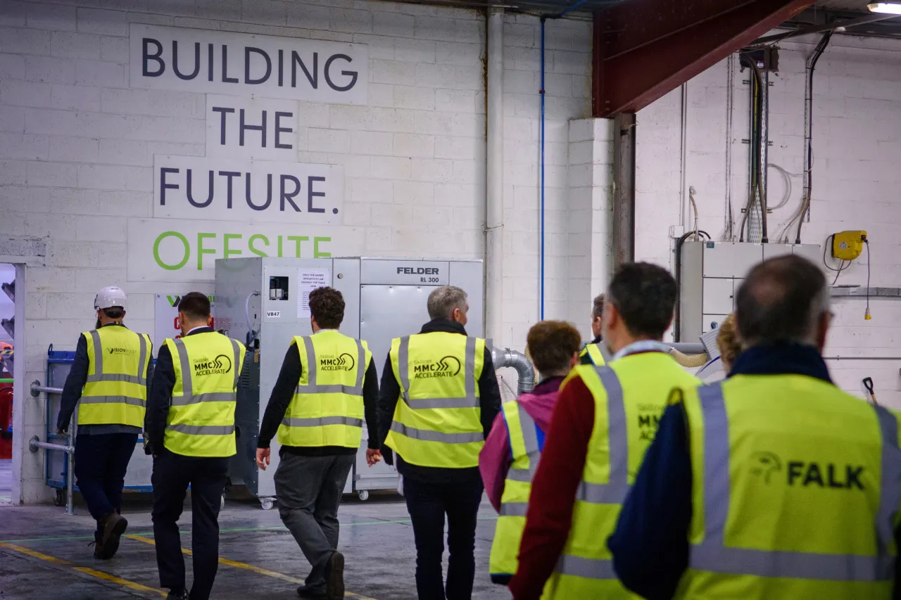 Group of construction workers in yellow safety vests at a site with "Building the Future" sign.