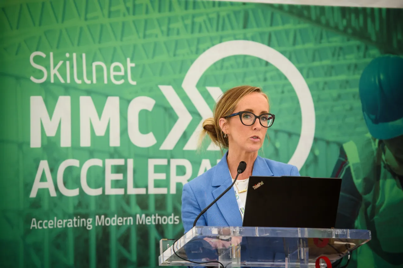 Person speaking at podium with Skillnet MMC Accelerate logo on green background.