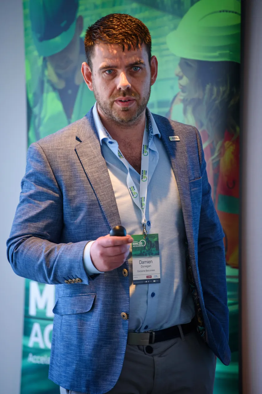 Person in a blue suit jacket and light blue shirt holding an award against a colorful backdrop.