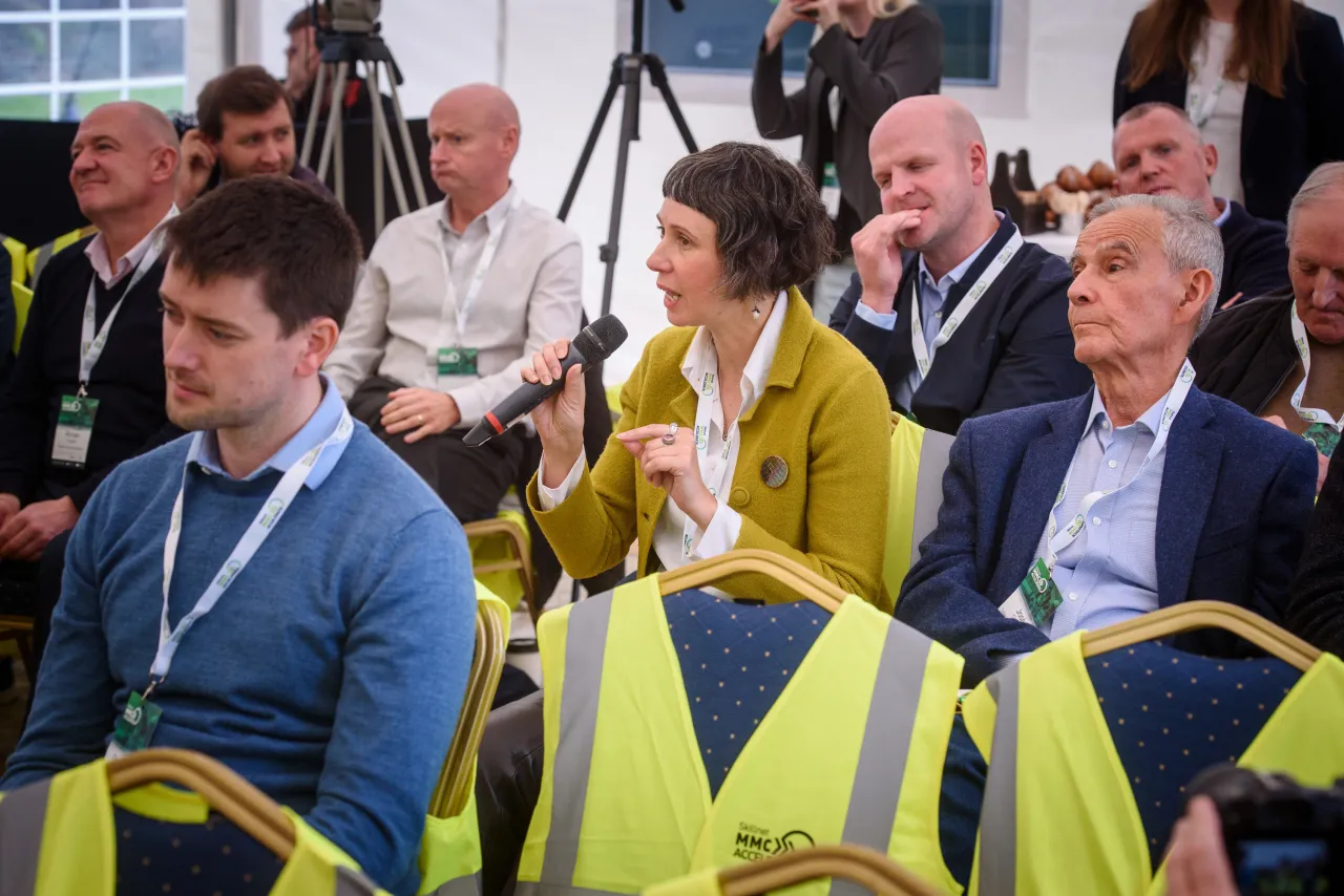 Conference attendees in yellow vests seated in audience during a presentation.