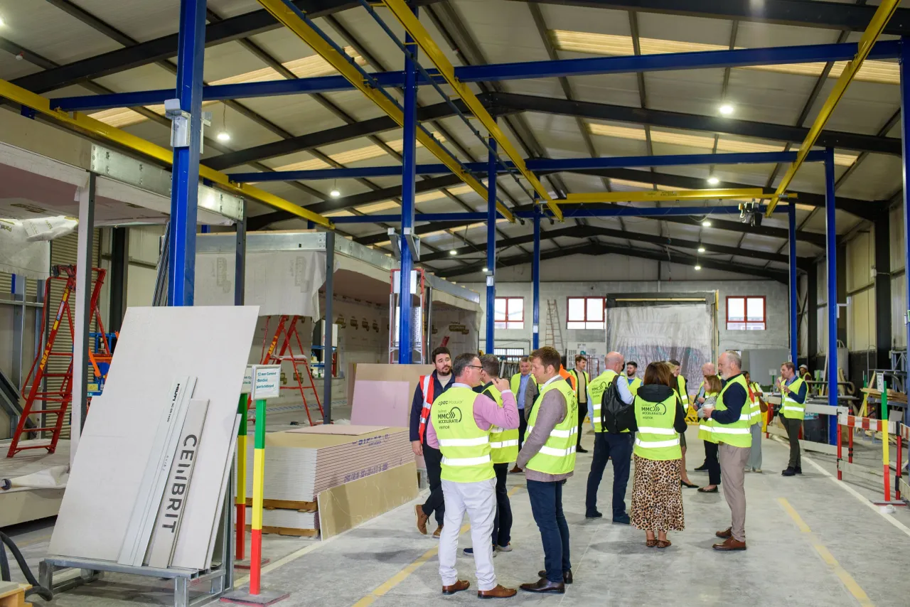 Construction workers in high-visibility vests inspecting a warehouse with blue support beams.