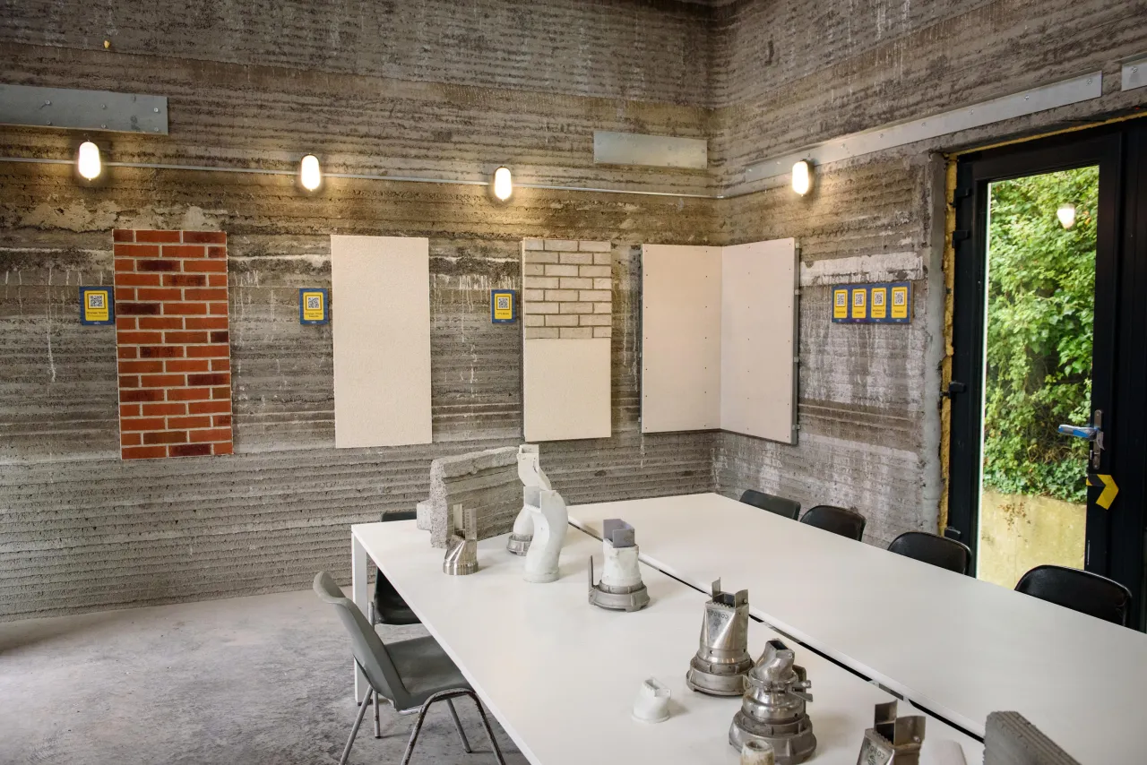 Rustic concrete bathroom with white sinks, exposed brick, and natural light.