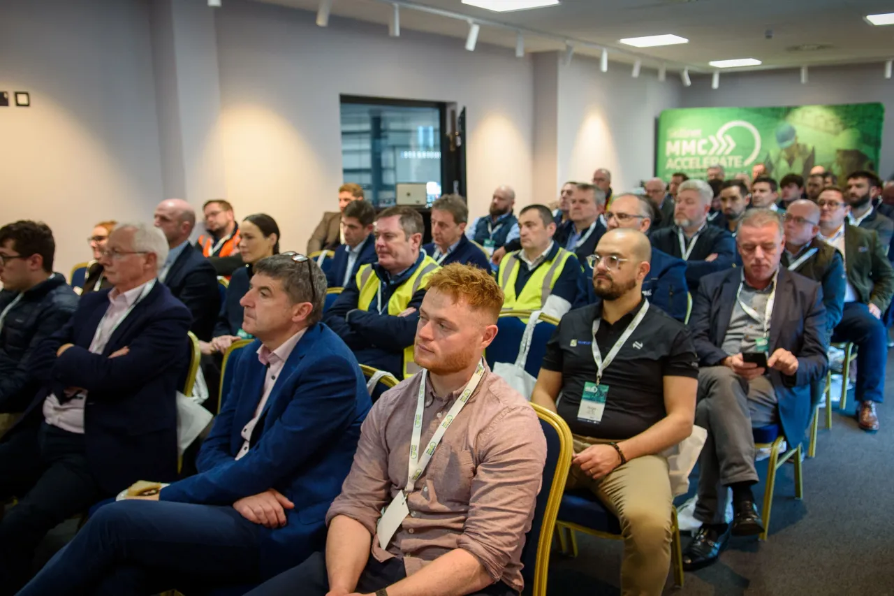 Conference attendees sitting in rows at a business presentation in a modern meeting space.