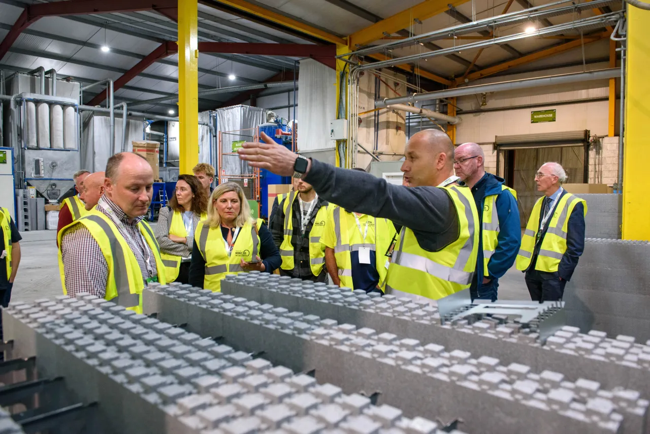Group of workers in high-visibility vests inspecting an industrial assembly line.