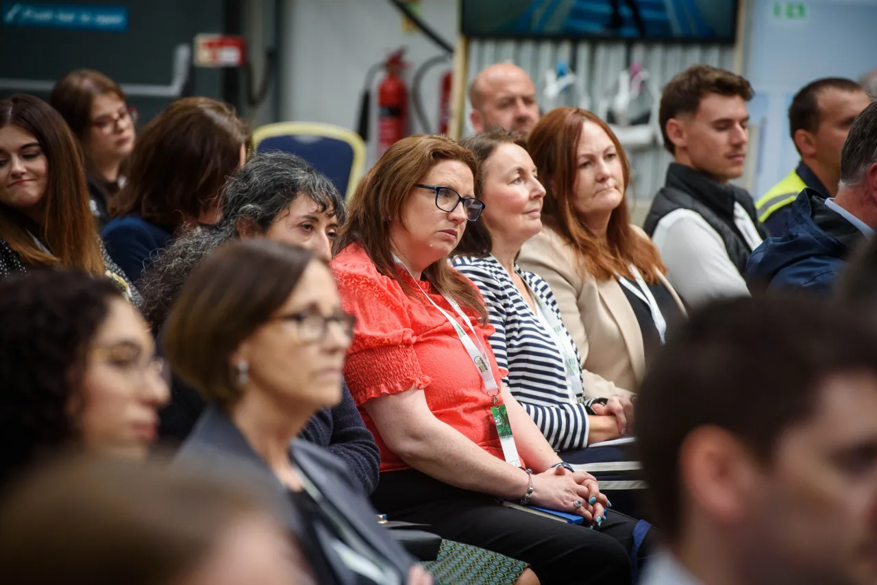Audience members attentively watching at an indoor event or conference.