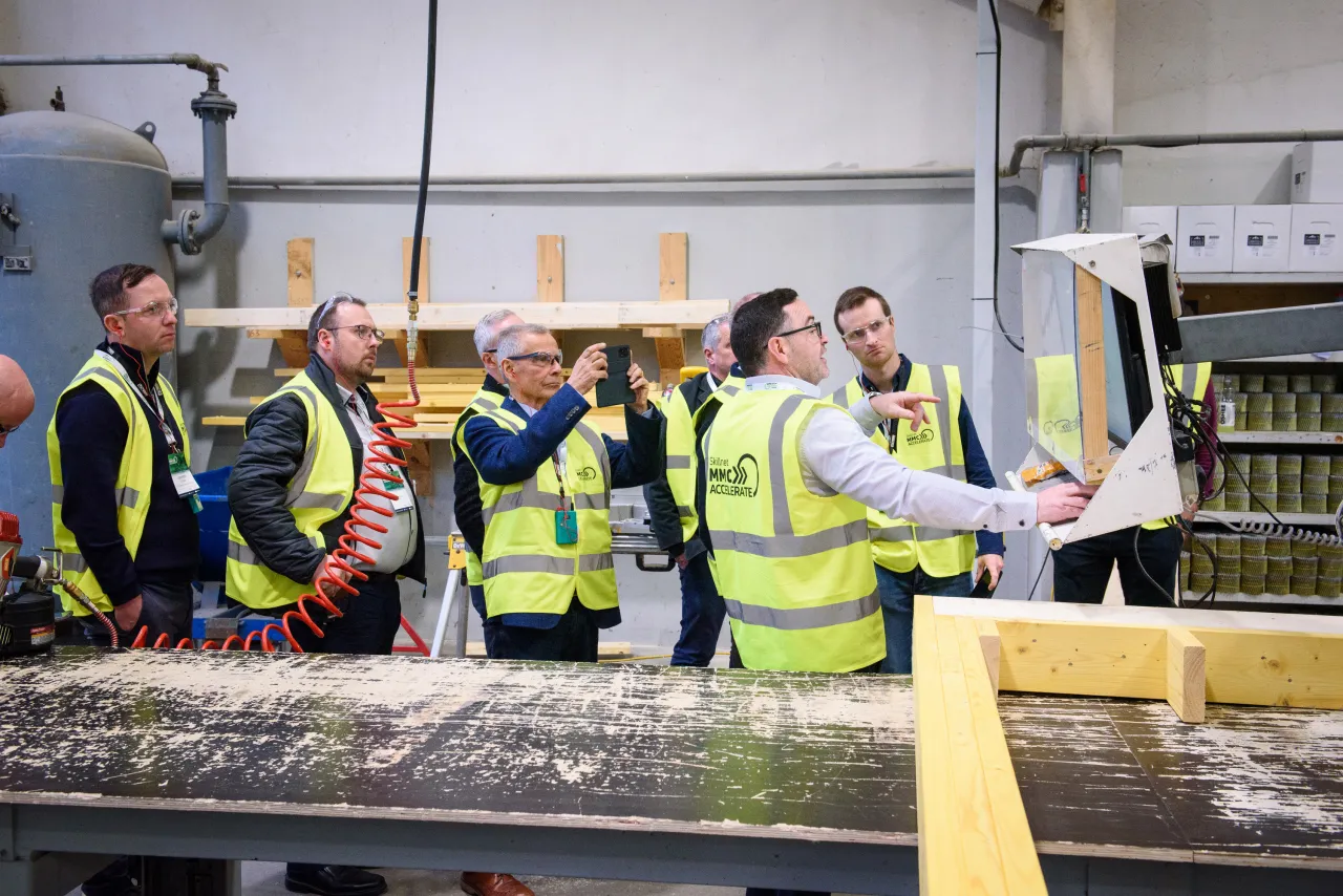 Workers in yellow safety vests on a production line in an industrial facility.