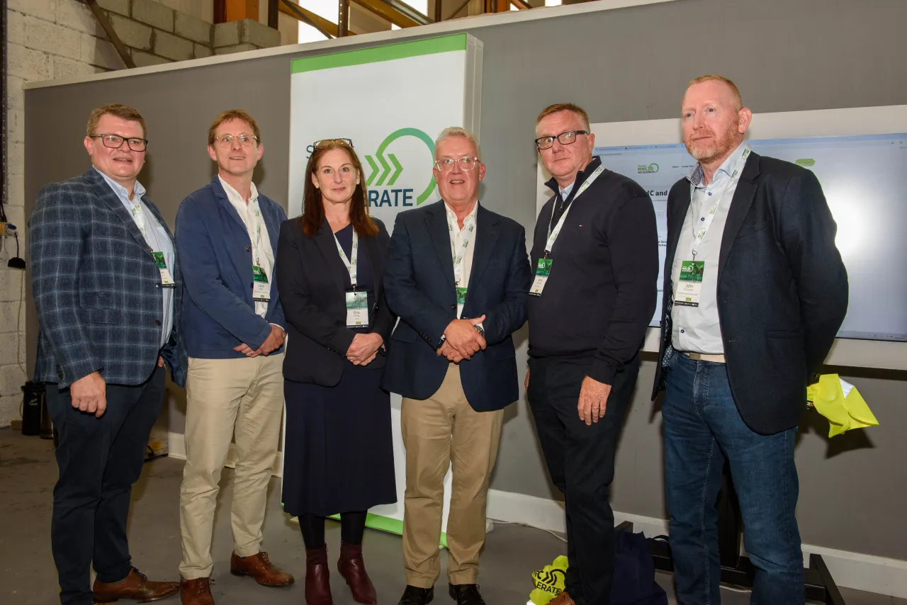 Group of people standing together in formal attire in front of a display screen.