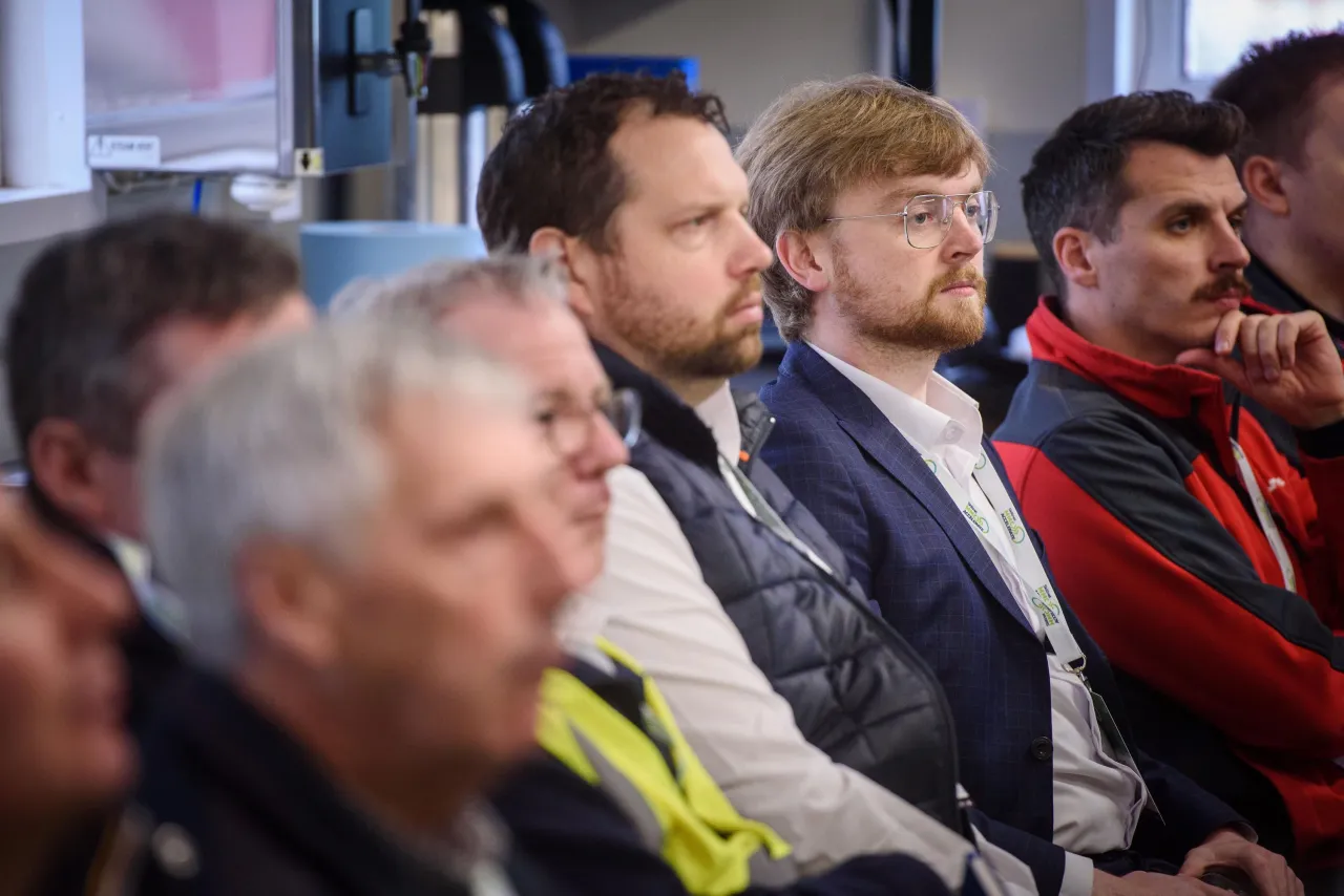 A group of people sitting in an audience, watching a presentation or event.