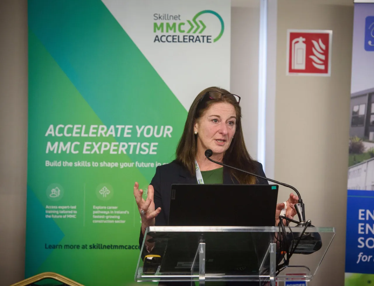 Person speaking at a podium with a green banner displaying "ACCELERATE YOUR WINE EXPERTISE" in the background.