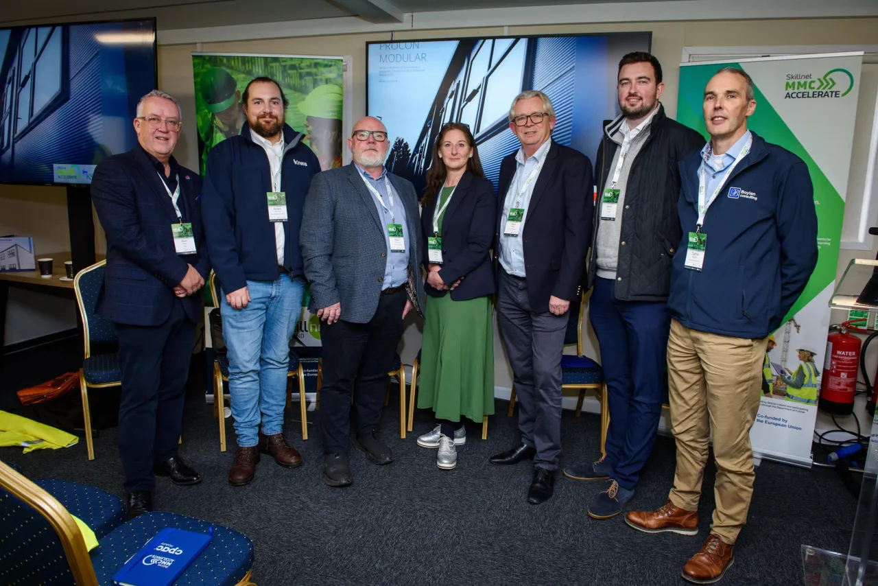 Group of people standing in what appears to be a club or organization room with equipment and banners visible.
