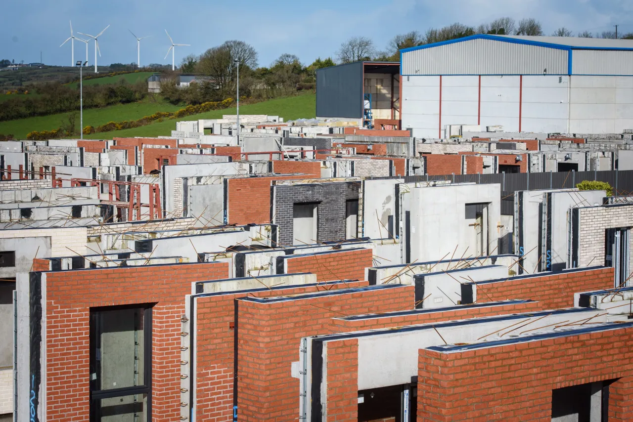 Rows of modern brick houses under construction in a dense residential development, overcast sky.