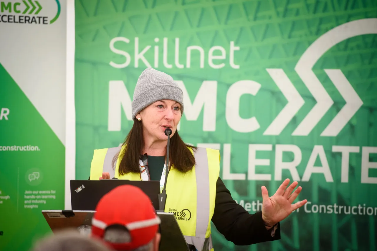 Woman in yellow safety vest speaking at Skillnet MMC Accelerate construction event.