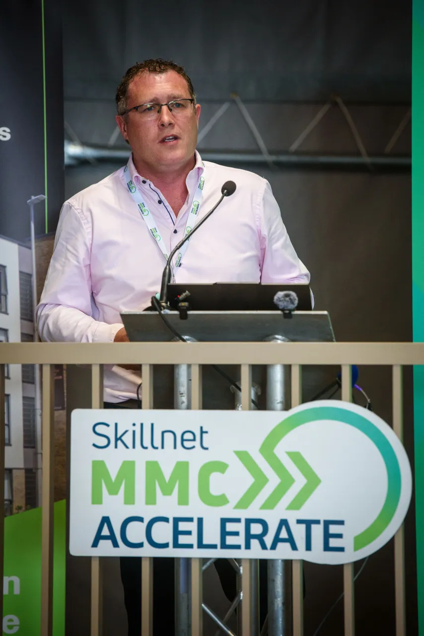 Man speaking at a Skillnet MMC Accelerate podium during a conference event.
