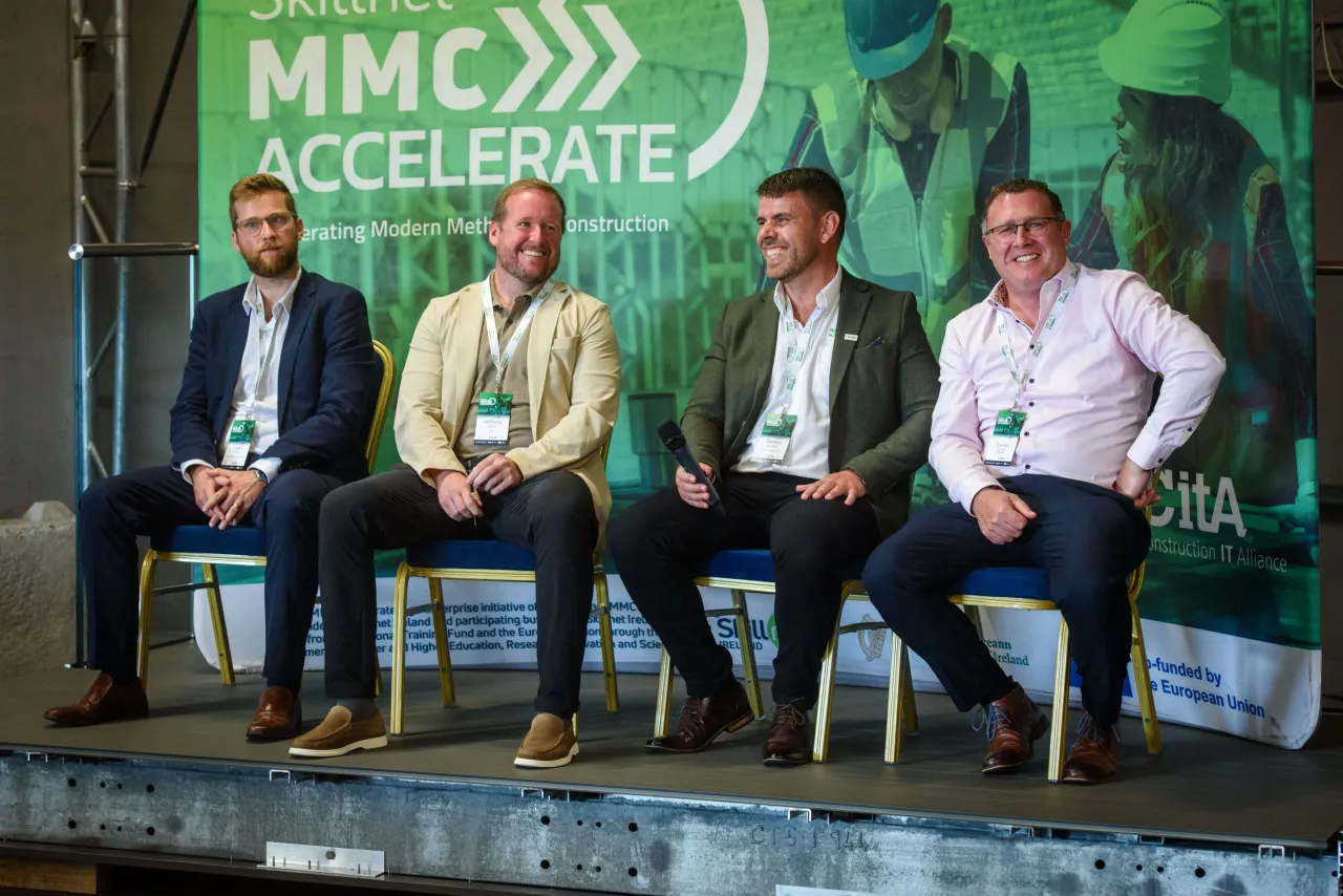 Four men seated in a row at the MMC Accelerate conference event.