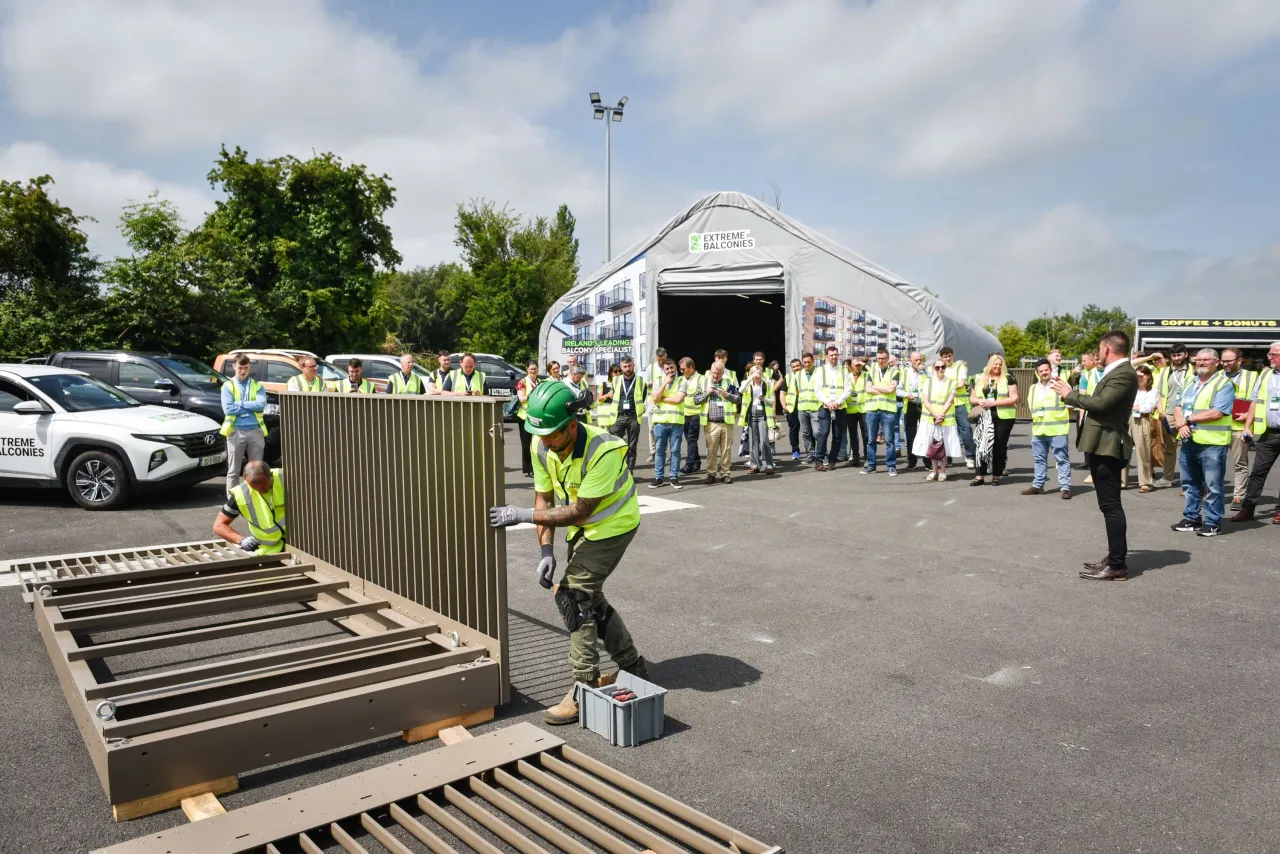 Workers in safety vests and hard hats gathered outdoors at an industrial facility during a demonstration.