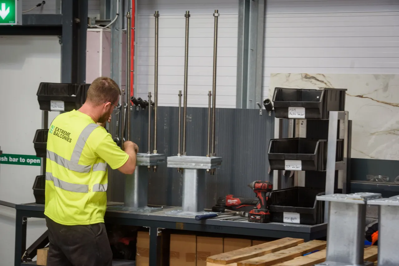 Worker in high-visibility vest operating industrial machinery in a warehouse setting.