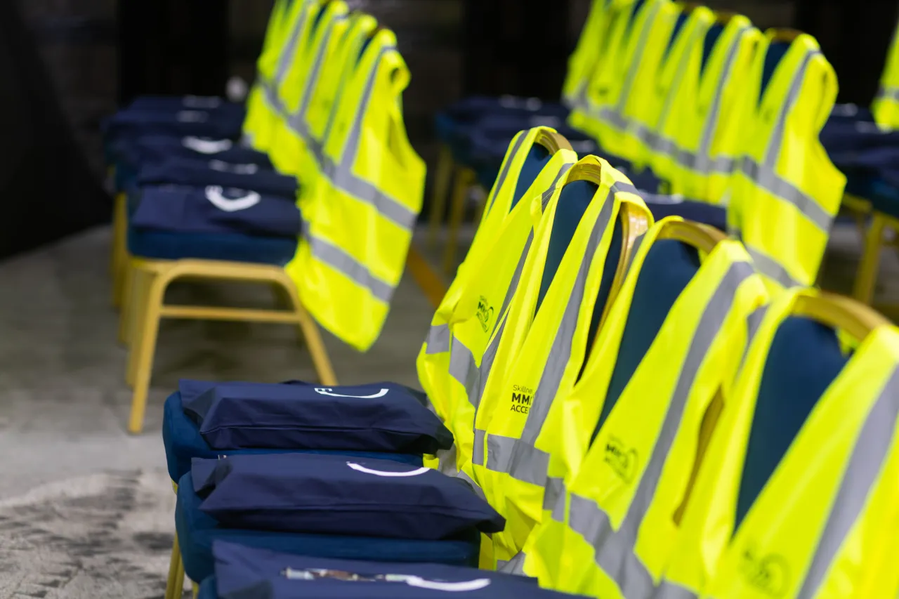 Yellow high-visibility vests draped over a row of chairs with blue seat cushions.