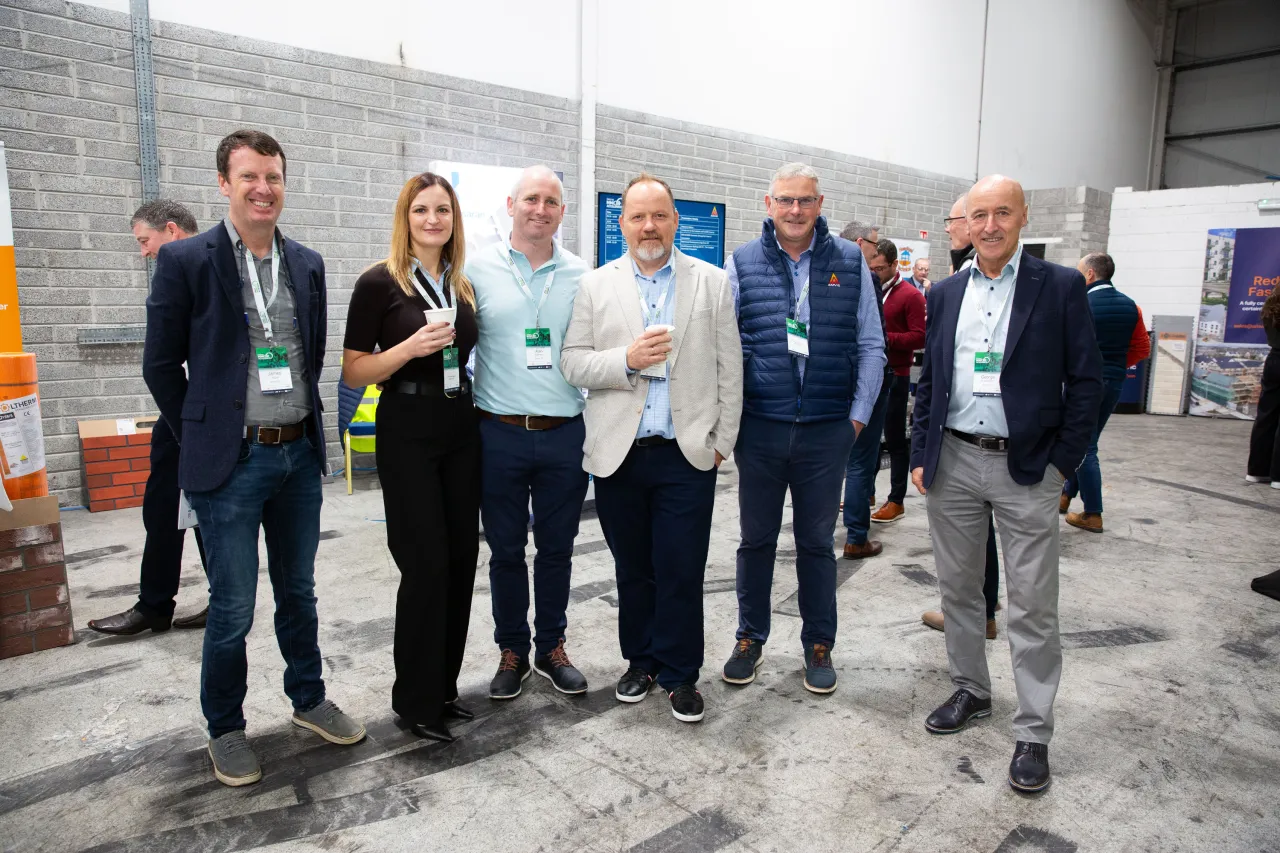 Group of seven professionals posing together at an indoor trade show or conference event.