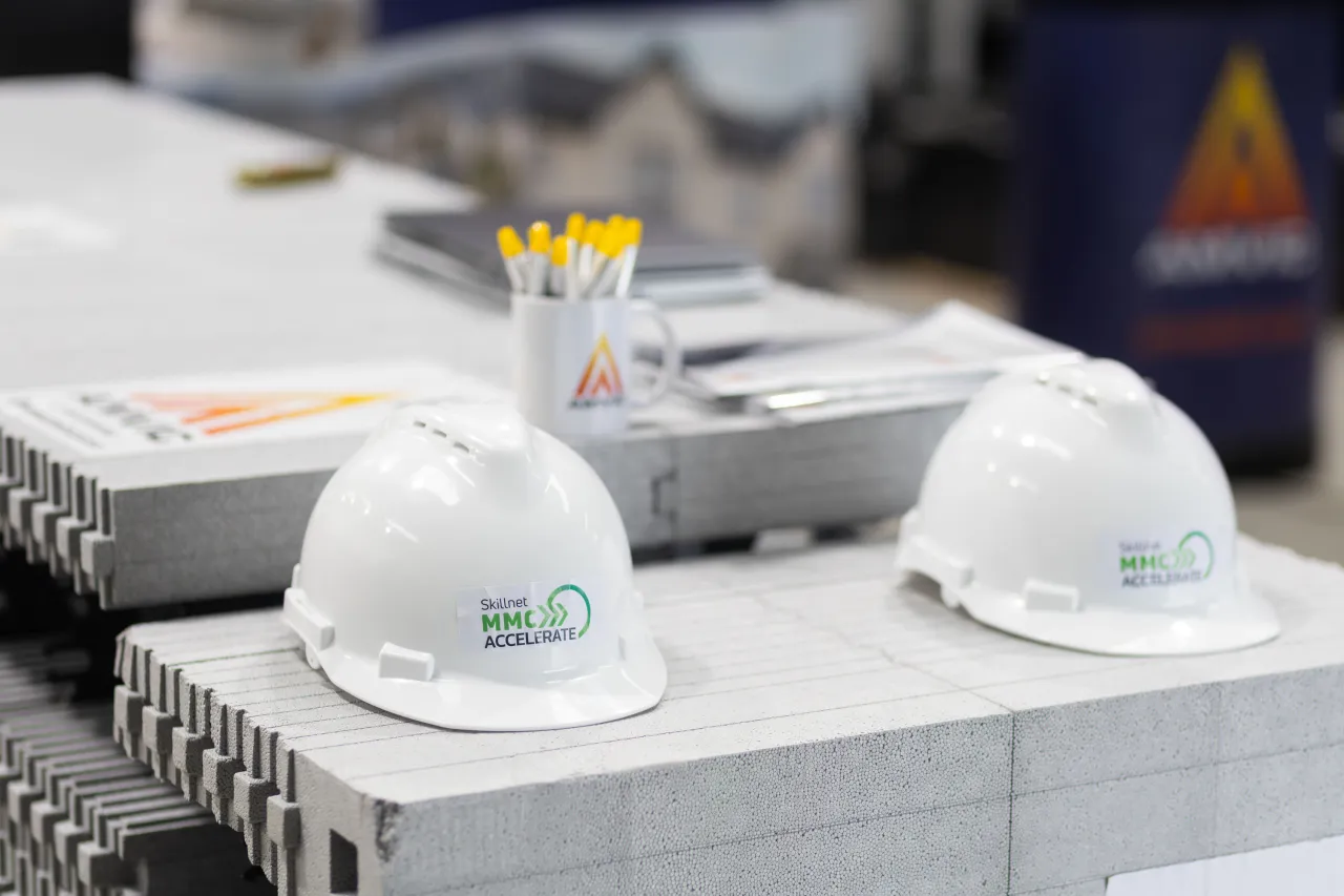 Two white construction hard hats resting on a concrete surface at a worksite.