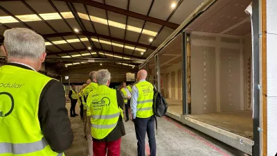 A group of people in high vis jackets inspect a manufacturing facility.