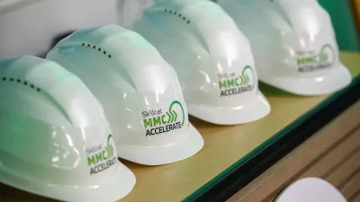 White hard hats are placed on the table, featuring the Skillnet MMC Accelerate logo.