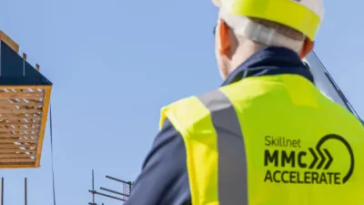 Person wearing a hard hat and high-vis vest looking at a construction site.