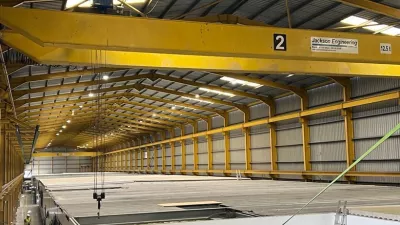 A large yellow crane over a large manufacturing facility.