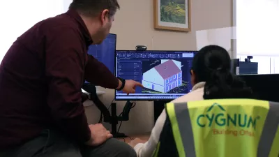 Two people in an office reviewing a 3D building model on a computer screen
