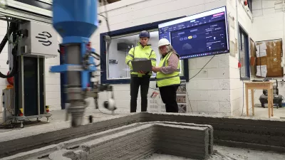 Two people operating a 3D concrete printing machine.
