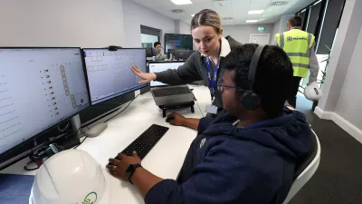 Two people are at a workstation, one is showing construction drawings on the screen to the other.