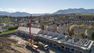 A large crane operating next to a number of houses under construction.