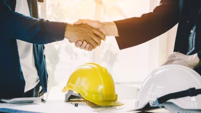 Two people wearing shirts shaking hands.