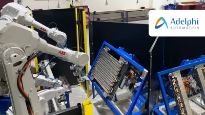 Industrial robotic arms working on components mounted in blue frames inside a manufacturing or training facility. Workbenches and tools are visible in the background.