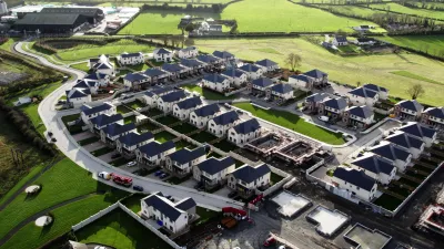 Aerial view of a residential housing development surrounded by green fields.