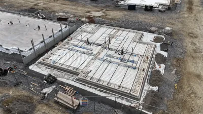 Construction site with a concrete foundation and visible underfloor heating pipes installed.