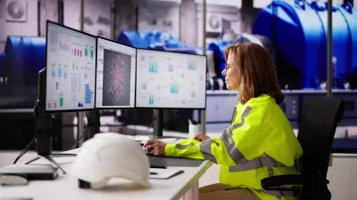 Engineer in a high-visibility jacket monitoring industrial process dashboards