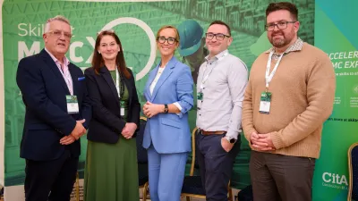 Five people standing together in front of a green Skillnet MMC Accelerate event banner, facing the camera and smiling.