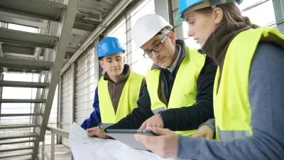 A group of engineers reviewing building plans on a construction site.