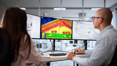 Two people looking at thermal imaging of a building on computer monitors.