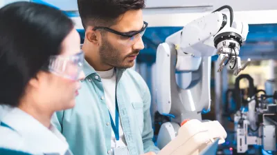 Two researchers examining a robotic arm in a laboratory setting.
