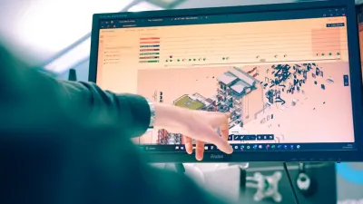 Person pointing at a computer screen displaying a detailed 3D building design model.