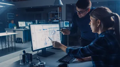Two professionals analyzing data on computer screens in a dimly lit technical environment.