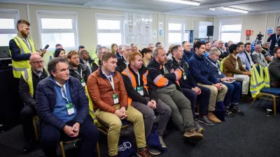 A group of people seated in rows at what appears to be a workplace meeting or safety briefing.