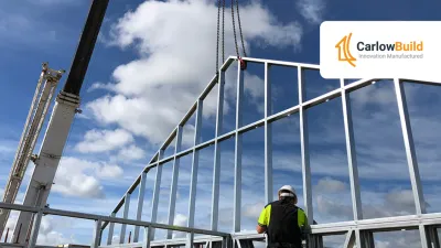 Construction worker in safety gear inspecting steel frame building structure against blue sky