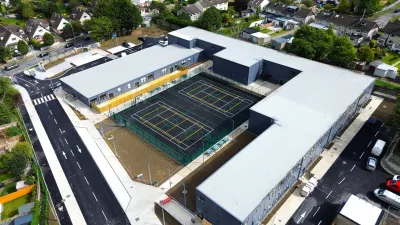 Aerial view of a white school building with tennis courts in the central courtyard.